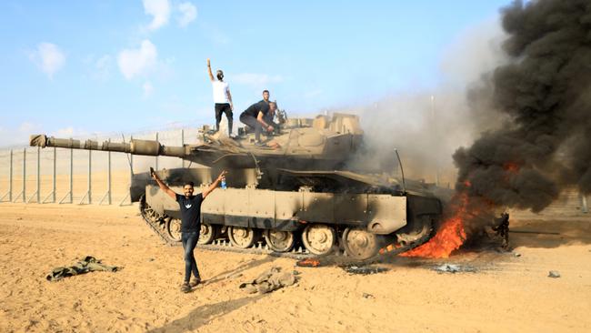 Palestinians celebrate on an Israeli tank near the fence of the Gaza-Israel border. Picture: Yasser Qudih/Xinhua via Getty Images