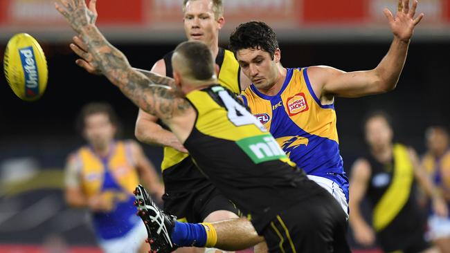 Tom Barrass gets a kick away as Dustin Martin attempts to spoil. Picture: Matt Roberts/AFL Photos/via Getty Images