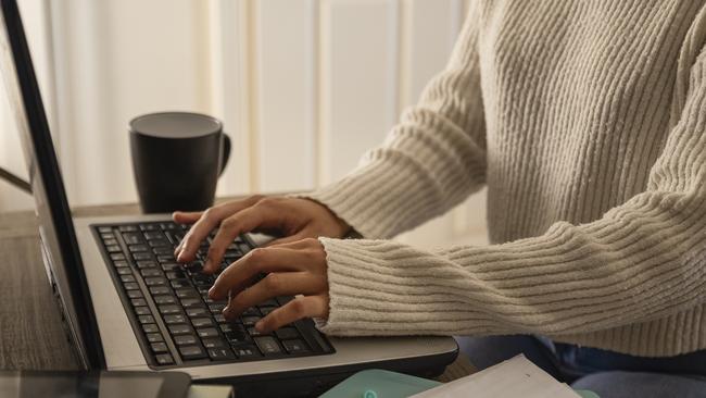 An unrecognisable young woman using her laptop and completing some work at home in Northumberland, North East England.