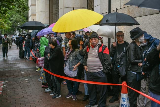 People queue outside a Hong Kong court where dozens of the city's most prominent democracy campaigners are set to be sentenced for subversion