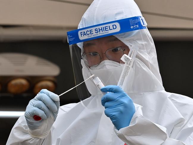 A medical staffer wearing protective gear takes a swab in Seoul.