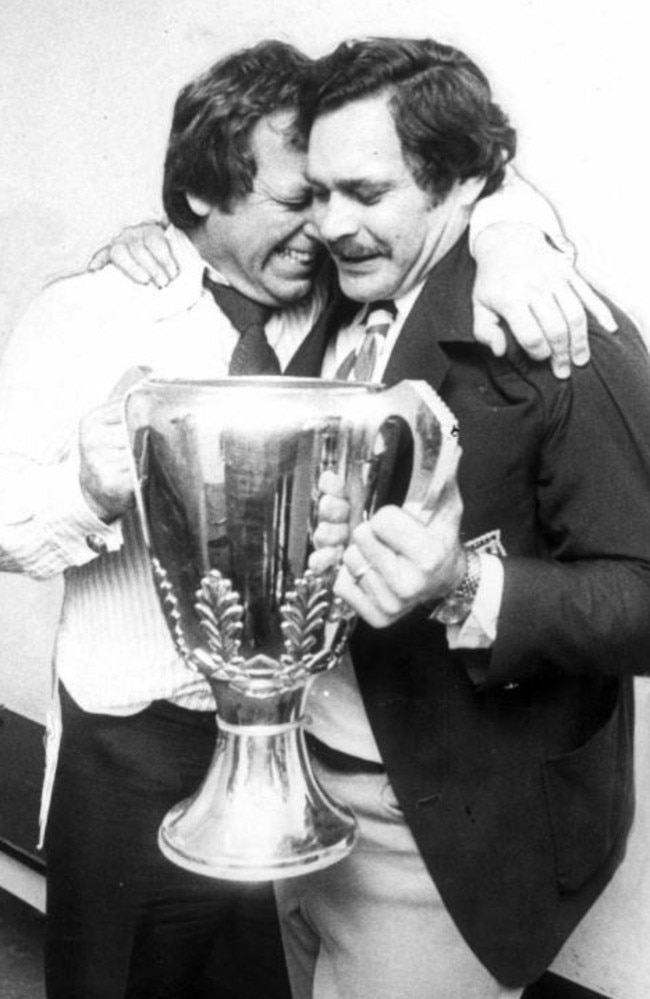 North Melbourne president Allen Aylett and Barassi hug while holding the 1975 premiership cup.