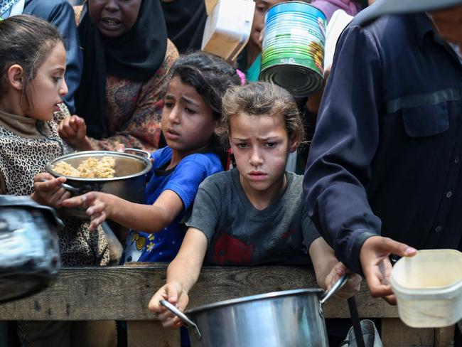 Palestinians gather to receive a hot meal at a food distribution point in the Nuseirat camp for refugees in the central Gaza Strip on May 21, 2025. Gazans waited desperately for vital supplies on May 21 after Israel said it let in dozens of UN trucks but faced mounting international pressure to increase the aid flow and abandon its intensified military campaign. (Photo by Eyad BABA / AFP)