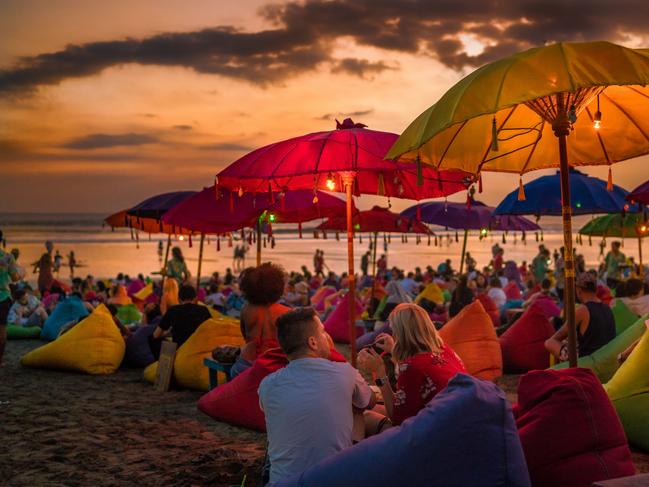 Denpasar, Bali, Indonesia - 17 June 2018: Tourists relaxing and sitting on colorful bean bags, under the umbrellas, and enjoying the sunset at the beach.Escape 18 June 2023Doc HolidayPhoto - Getty Images