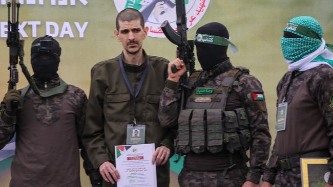 Palestinian Hamas fighters escort Eli Sharabi on a stage before handing him over to a Red Cross team in Deir el-Balah. Picture: AFP.