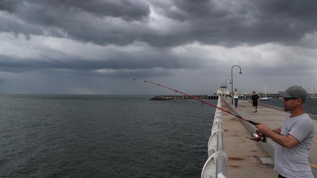 Storm? What storm? Bad weather doesn’t put off this fisherman at St Kilda. Picture: David Crosling