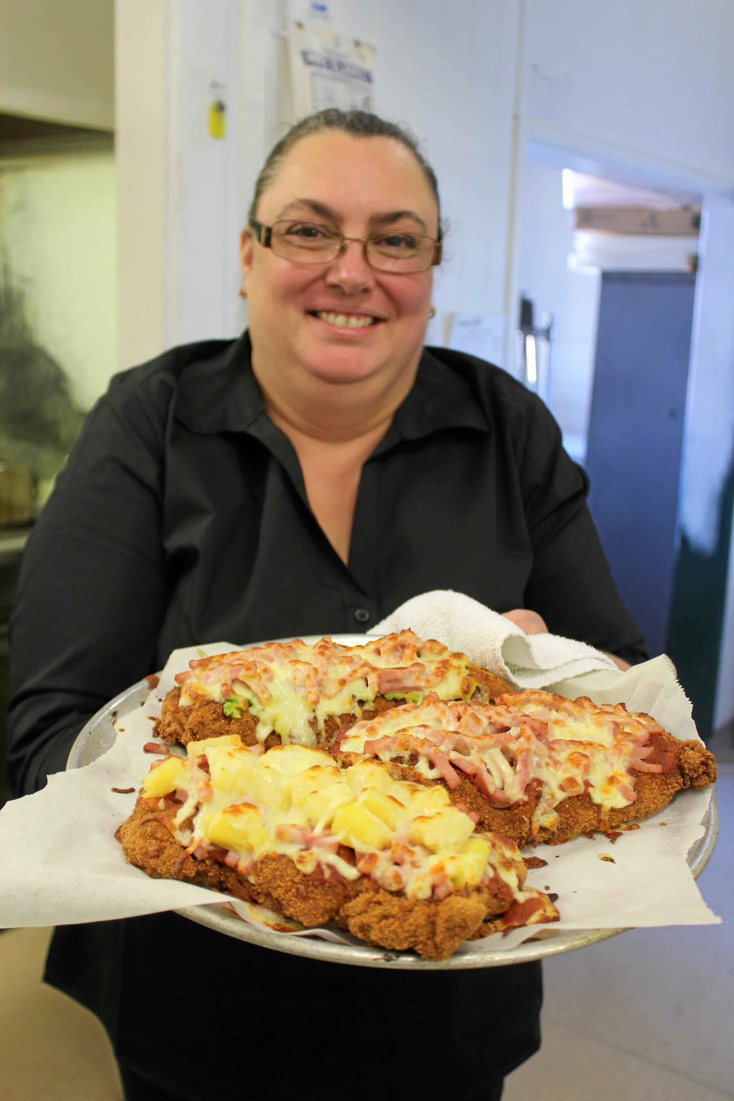 Head Cook Stacey Ellwood showcasing the Hawaiian, Golden Buick and Traditional Chicken Parmies that just freshly came out of the oven. Picture: Laura Blackmore