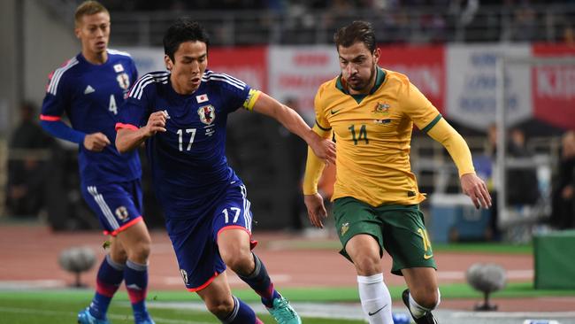 James Troisi of Australia dribbles the ball under the pressure from Makoto Hasebe.