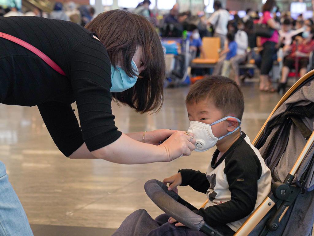 A woman puts a mask on her young son at Changi Airport in Singapore on Saturday, as the city confirmed its third case of the deadly coronavirus. Picture: Ore Huiying/Getty Images