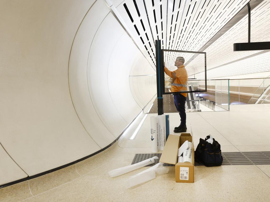 A worker putting up a station map at the entrance to Victoria Cross Metro Station. Picture: Richard Dobson