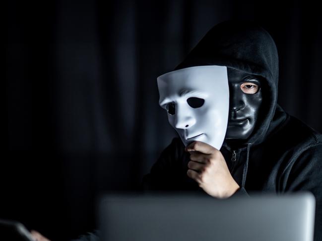 Stock image showing a man wearing a mask and a hoodie with laptop computer on the table. Anonymous social masking. Ransomware cyber attack or internet security concepts. Picture: istock