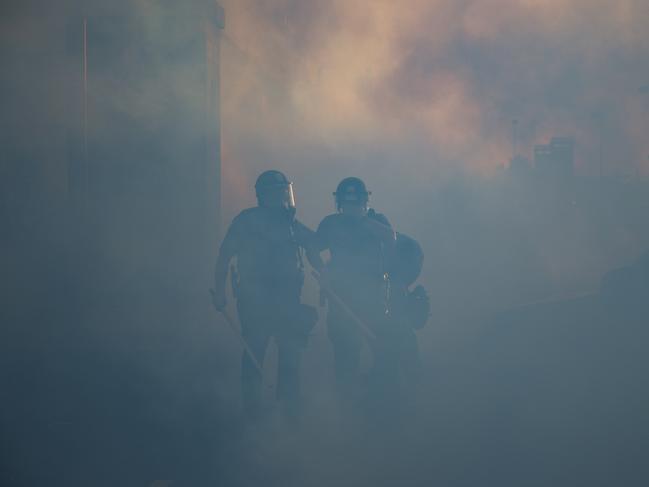 Police officers walk through a cloud of tear gas in St. Paul, Minneapolis. Picture: AP