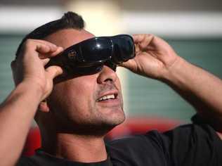 Joe Murphy, of Currumbin, looks through six pairs of sunglasses to view the eclipse. Picture: John Gass