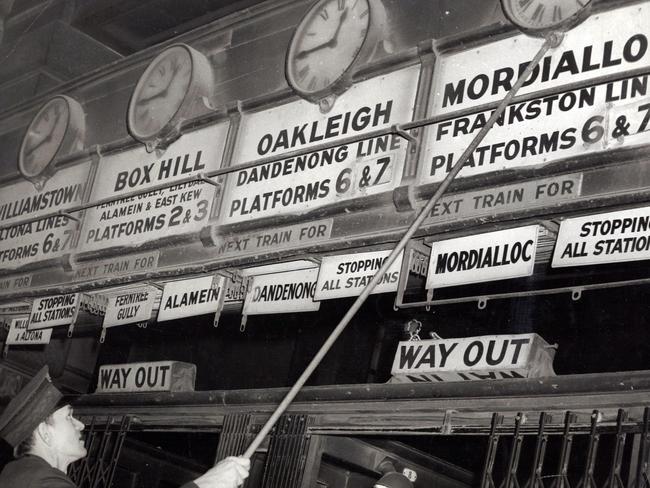 The station master manually changing the Flinders Street Station clocks. During an 8-hour period the clocks at the main entrance were changed an average of 900 times. Picture: HWT Library.