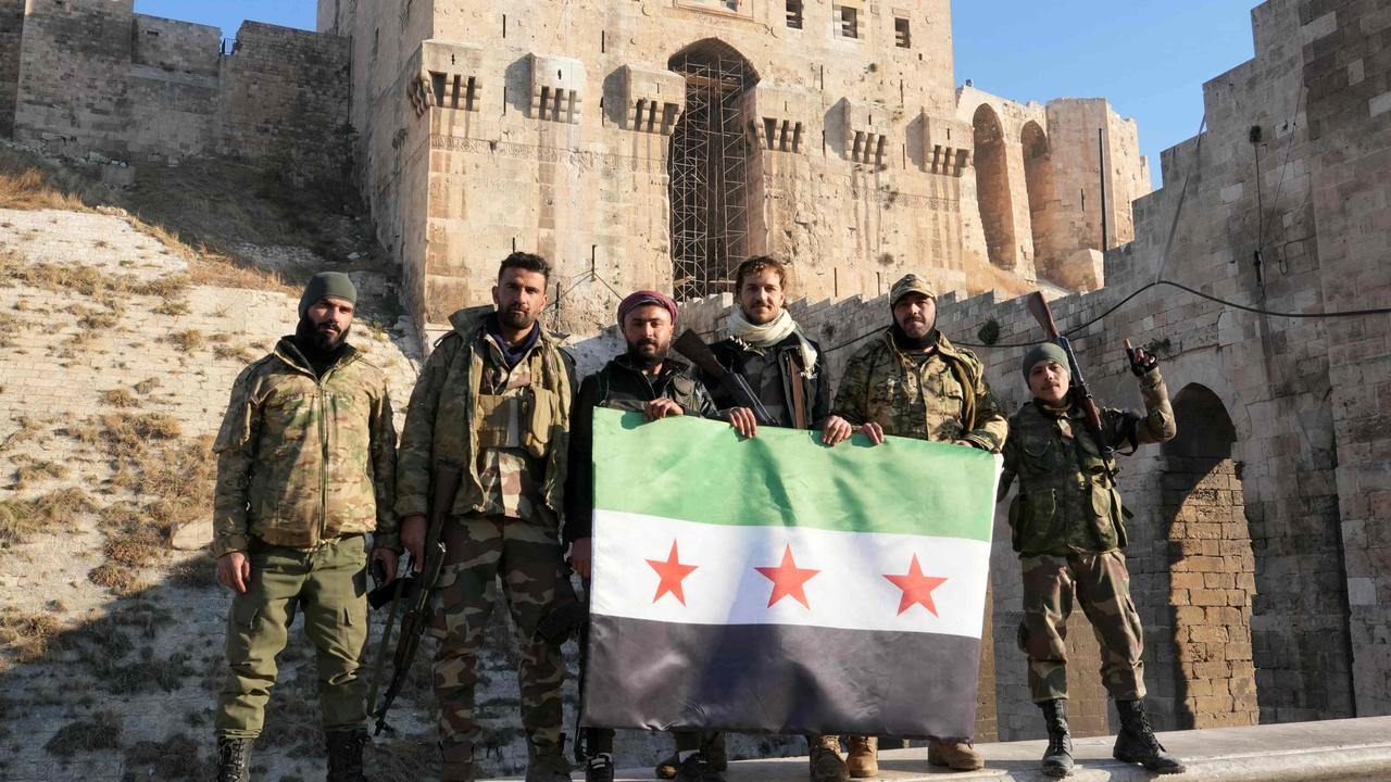 Anti-government fighters hold an opposition flag as they pose for a picture at the entrance of the landmark citadel in Aleppo. Picture: AFP