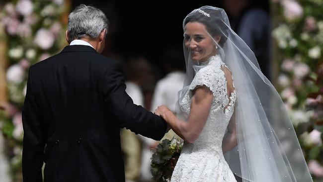 Pippa Middleton, (R) is escorted by her father Michael Middleton, as she arrives for her wedding to James Matthews at St Mark's Church in Englefield, west of London, on May 20, 2017. Pippa Middleton hit the headlines with a figure-hugging outfit at her sister Kate's wedding to Prince William but now the world-famous bridesmaid is becoming a bride herself. Once again, all eyes will be on her dress as the 33-year-old marries financier James Matthews on Saturday at a lavish society wedding where William and Kate's children will play starring roles. / AFP PHOTO / POOL / Justin TALLIS