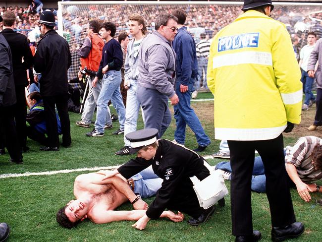 (FILES) In this file photo taken on April 15, 1989 emergency sevices personnel help soccer fans on the pitch at Hillsborough stadium, where 96 fans were crushed to death and hundreds injured during a match between Liverpool and Nottingham forest. - David Duckenfield, the police commander on duty at the 1989 Hillsborough stadium disaster, was found not guilty November 28, 2019 of the gross negligence manslaughter of 95 Liverpool fans who were crushed to death. (Photo by STRINGER / AFP)