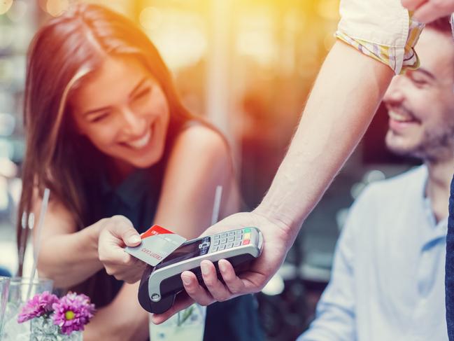 Smiling woman paying contactless with credit card +++++ NOTE for the inspector: Credit card is fake  and is made especially for the photosession +++++ Picture: iStock