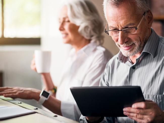 Daily life. Old grey man in glasses using laptop while woman drinking tea and smiling