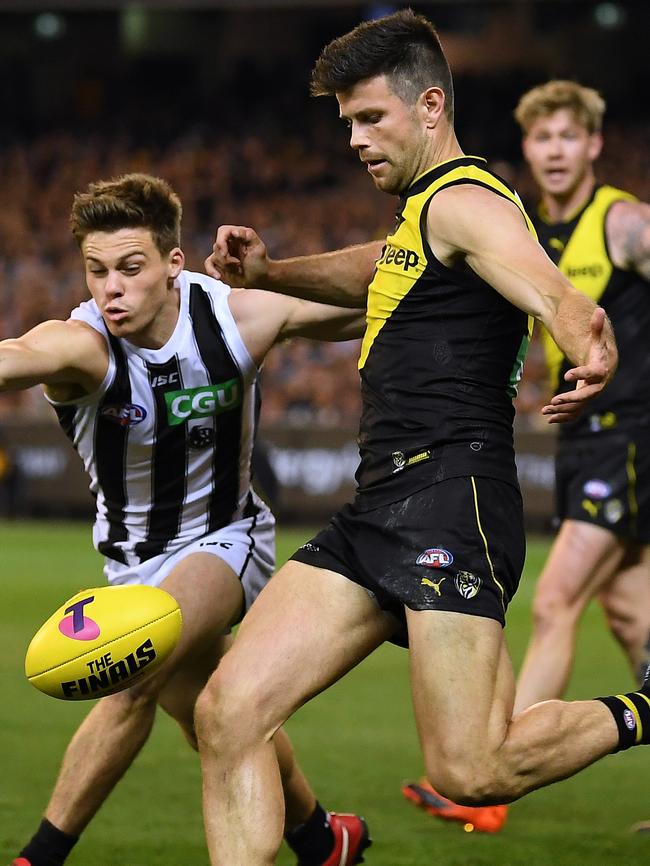 Trent Cotchin gets a kick away under pressure from Josh Thomas.