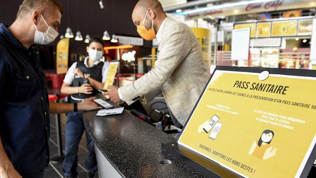 A French cinema employee checks a patron’s vaccine passport. Picture: Jean-Christophe Verhaegen / AFP