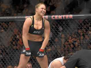 BIG NAME: Ronda Rousey, top, celebrates as Cat Zingano kneels on the mat during a UFC 184 mixed martial arts bantamweight title bout. Picture: Mark J. Terrill-AAP