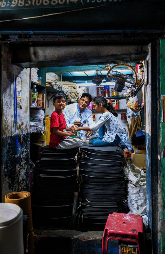 A family enjoys dinner together in their small shop in Kolkata, India, surrounded by stacked mats and shelves of goods. Their son smiles at the camera while the adult and the girl focus on their meal, reflecting a heartwarming moment of family unity and tradition. Picture: Laurin Strele/Pink Lady® Food Photographer of the Year