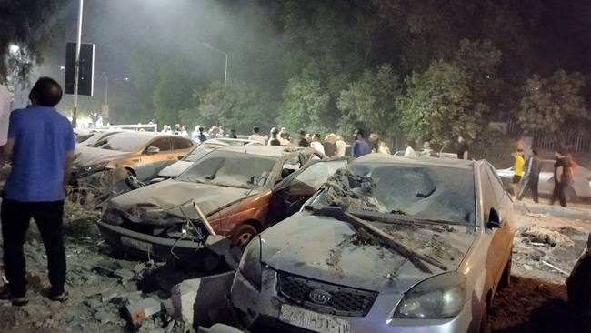 People gather by damaged vehicles at the site of a reported Israeli air strike on a residential building in Syria's capital Damascus on Tuesday. Picture: AFP