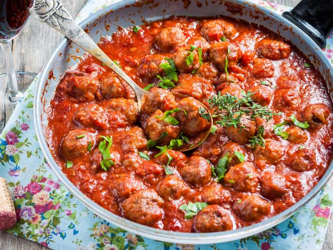 meatballs in tomato-wine sauce in a pan on a wooden background for Cairns Sun with recipe and article by Julia Wedding, March 21, 2017