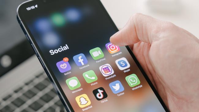 Gothenburg, Sweden - March 23, 2022: A man's hand holds a Iphone 13 Pro max with social media apps, against the background of a laptop. Blurred background. Selective focus. Picture: iStock