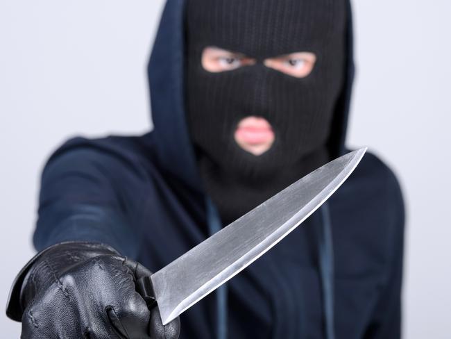 Masked man aims with knife. on gray background. Robbery, crime, knife generic