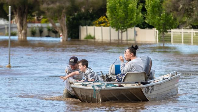 A young family being rescued after their home was flooded waist-deep in water during the floods. Picture: Jason Edwards