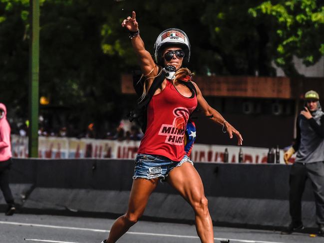 An opposition activist (Caterina Ciarcelluti) clashes with the police during a march against Venezuelan President Nicolas Maduro held on May Day, in Caracas on May 1, 2017. Security forces in riot vans blocked off central Caracas Monday as Venezuela braced for pro- and anti-government May Day protests one month after a wave of deadly political unrest erupted.  / AFP PHOTO / Juan BARRETO