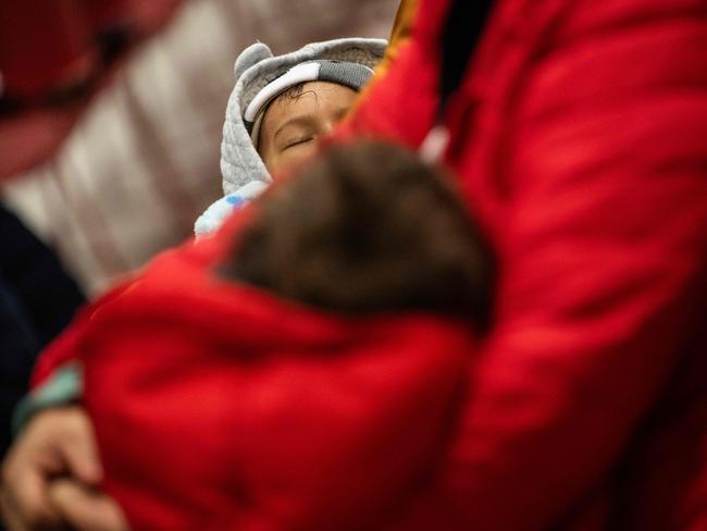 A boy sleeps in his mothers arms during an Amica Center for Immigrant Rights (formerly known as CAIR Coalition) presentation on immigration enforcement at a school in Washington, DC on January 10, 2025. In preparation for increased immigration enforcement, a DC school hosted a "know your rights" presentation given by Amica Center attorney, Atenas Burrola Estrada. Organized by concerned parents and open to members of the school and the community at large, attendees learned about their rights  in regards to Immigration Customs and Enforcement (ICE) raids and investigations that might effect themselves, their families, and their communities. (Photo by ANDREW CABALLERO-REYNOLDS / AFP)