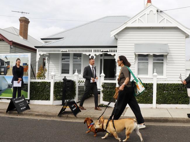 McGrath auctioneer David Cortous calls for bids as a dog walker passes along Albert St. 29 Albert St, Geelong West.