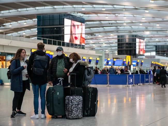 Airline passengers wearing face masks wait to check in their bags at Heathrow Terminal 5 departures as the outbreak of coronavirus intensifies in London, England. Picture: Getty