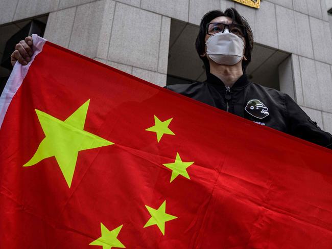 An man holds the national flag of China after a pro-Beijing activist group gathered outside the British Consulate-General to protest against the use of the British National (Overseas) passport in Hong Kong on February 1, 2021, as a new visa scheme offering millions of Hong Kongers a pathway to British citizenship went live the day before. (Photo by Anthony WALLACE / AFP)