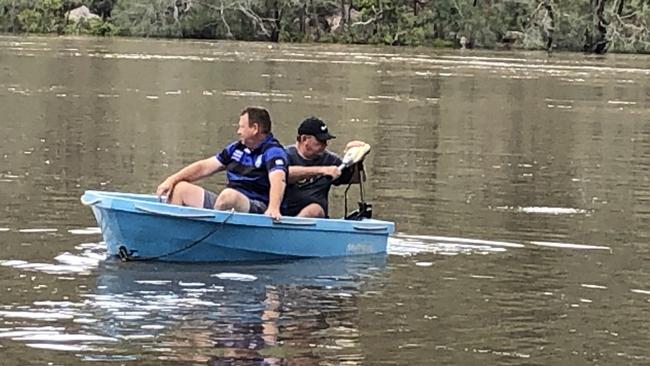 Boat driver Darren Mercer helps neighbour Dave Wiley to get to his Picnic Point home on Monday Picture: Lawrence Machado