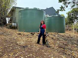 RUNNING ON EMPTY: Mishaela Simpkins, from Mullumbimby Creek, stands beside her twin 20,000 litre tanks that are all but empty due to the drought. Picture: Christian Morrow