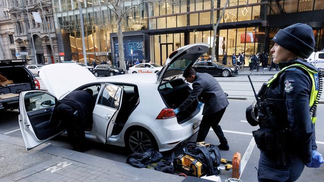 Police search through a white hatchback on Collins st after a major police incident with people reporting they were told to stay inside their office buildings. Picture: David Geraghty / NewsWire