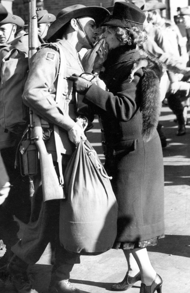 A soldier and a woman share a farewell kiss as he heads off to fight during WWII.