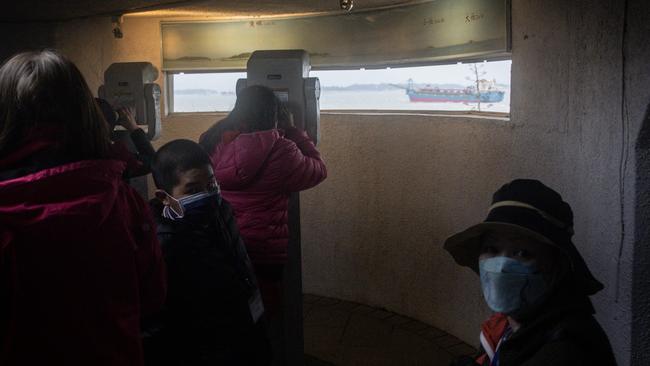 Tourists take photographs of the Chinese mainland and Chinese flagged sand dredgers from the bunker of an old Taiwan military observatory on Sunday in Kinmen, Taiwan. Picture: Getty