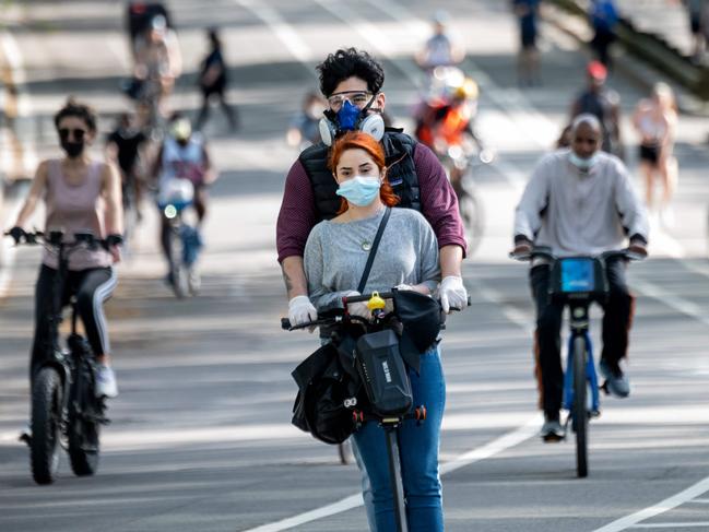 People wearing masks ride in Central Park as New Yorkers are straining to leave lockdown and get some sunshine and exercise. Picture: AFP