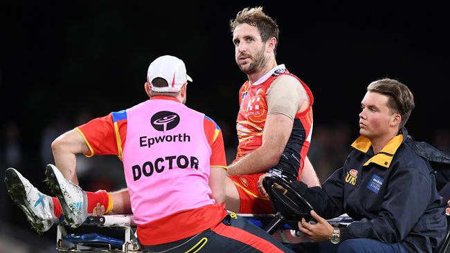 Gold Coast midfielder Michael Barlow is carted off after suffering a graphic injury. (AAP Image/Dave Hunt)
