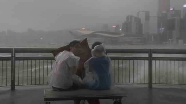 Locals are buffeted by strong winds from Typhoon Hato on the waterfront of Victoria Harbour in Hong Kong. Picture: AP/Vincent Yu