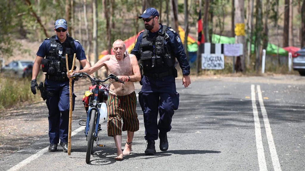 Police escort a man near a protest at Deebing Creek. Picture: Cordell Richardson