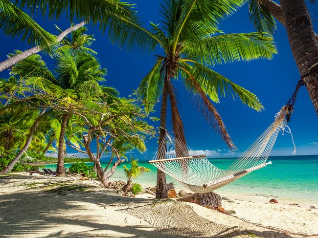 Empty hammock in the shade of palm trees on tropical Fiji Islands