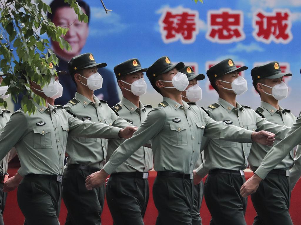 Chinese People's Liberation Army (PLA) soldiers wearing face masks to protect against the spread of the new coronavirus march past a banner of President Xi Jinping. Picture: AP Photo/Andy Wong.