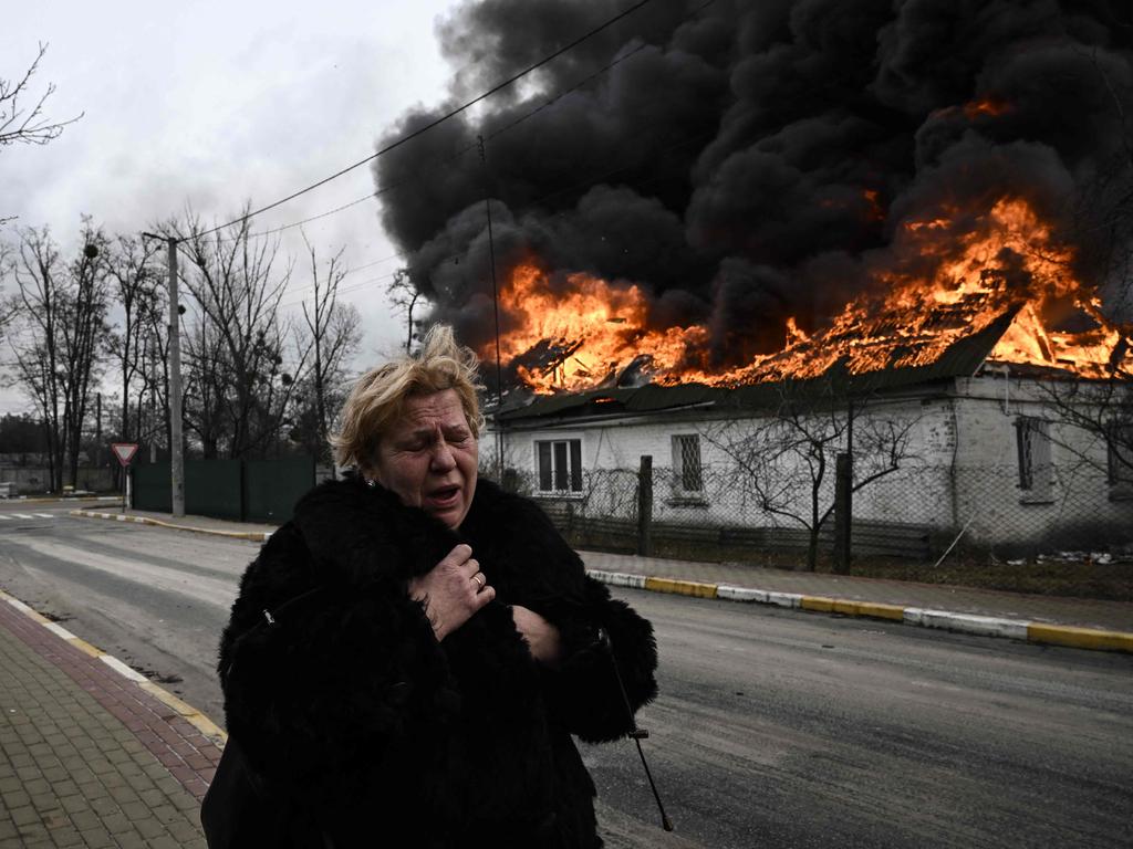 A woman reacts as she stands in front of a house burning after being shelled in the city of Irpin, outside Kyiv, on March 4, 2022. Picture: Aris Messinis / AFP