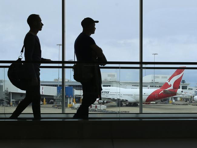 SYDNEY, AUSTRALIA - MARCH 10: Two passengers walk past a Qantas jet at the International terminal at Sydney Airport on March 10, 2020 in Sydney, Australia. Qantas has cut almost a quarter of its international capacity for the next six months as travel demands fall due to fears over COVID-19. The airline today announced it was altering routes to London and would be parking eight of their 12 A380 aircraft. (Photo by Mark Evans/Getty Images)